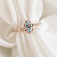 a ring that is sitting on top of a white cloth with a blue stone in the center