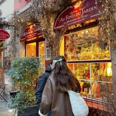 a woman walking down the street in front of a store with lots of christmas decorations