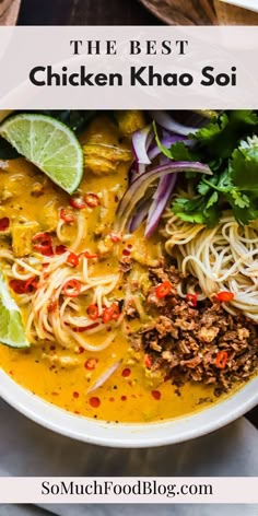 a white bowl filled with noodles, meat and veggies on top of a wooden table