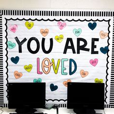 two computer desks sitting next to each other in front of a sign that says you are loved