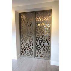 an intricately designed metal door in the corner of a room with hardwood floors and white walls