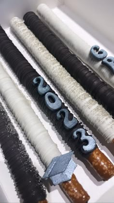 an assortment of decorated desserts are displayed in a white box with blue and black icing