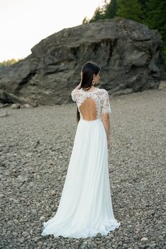 a woman in a white dress standing on rocks