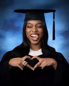 a woman wearing a graduation cap and gown making a heart with her hands