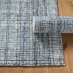 a blue and white rug on top of a wooden floor next to a chair with an arm rest