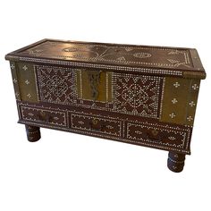 an ornately decorated wooden chest with metal accents on the front and sides, against a white background