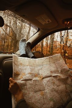 someone holding up a map in the back seat of a car