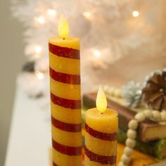 two candles sitting on top of a table next to a christmas tree and other decorations