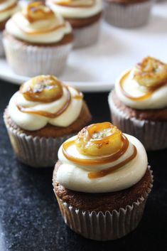 some cupcakes with white frosting and bananas on top are sitting on a plate