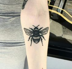 a black and white bee tattoo on the arm