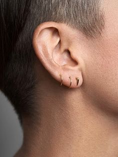 a close up of a person's ear with two small gold hoops on it