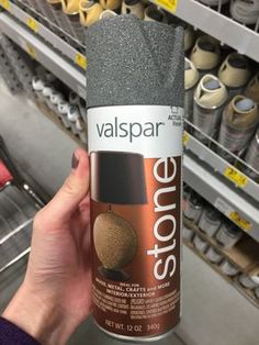 a person holding up a can of valpspar stone paint in a store