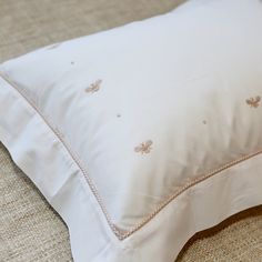 a white pillow sitting on top of a bed next to a beige blanket and pillows