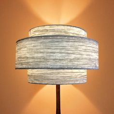 a lamp that is on top of a wooden table next to a wall with a light coming from it