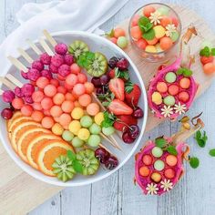 a bowl filled with fruit on top of a wooden cutting board