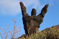 a rock formation with two hands reaching up into the sky