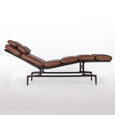 a brown leather chaise lounge chair sitting on top of a metal frame