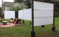 an outdoor area with chairs, tables and a white privacy screen in the middle of it