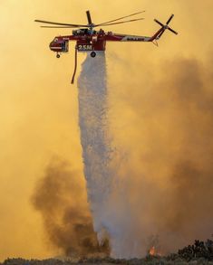 a helicopter dropping water from a fire hydrant with it's landing gear in the air