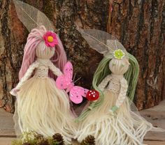 two fairy figurines sitting next to a tree