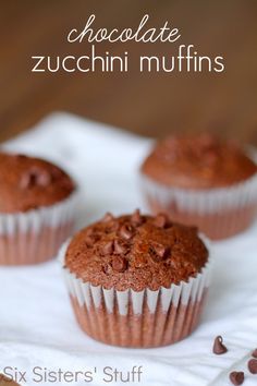 three chocolate zucchini muffins sitting on top of a white napkin with chocolate chips