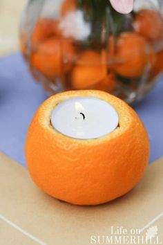 an orange sitting on top of a table next to a vase with flowers in it