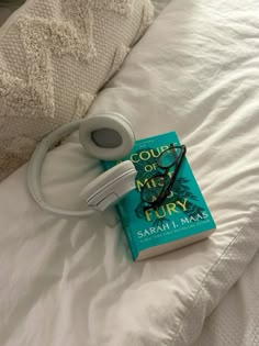 a book and headphones laying on top of a bed