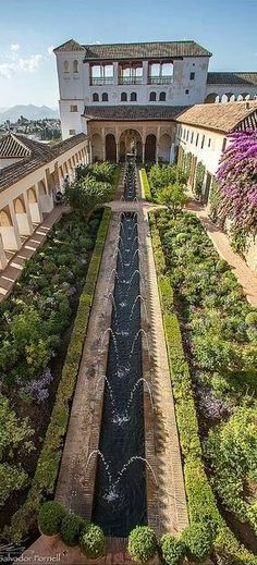 an aerial view of a building with a garden in the foreground and water running through it