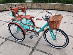 a blue bicycle with a basket on the front parked in a circular area next to a stone wall