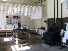 an old fashioned room with several pieces of furniture hanging from the ceiling and clothes drying on racks