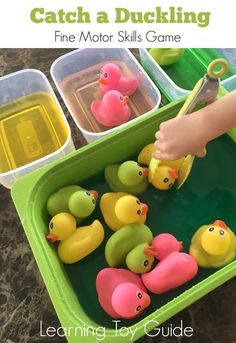 a child's hand holding a pair of scissors in a tub filled with rubber ducks