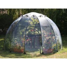 a small greenhouse with plants growing inside and in it's side walls, sitting on the grass