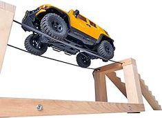 a yellow toy truck is on top of a wooden structure and being pulled by a rope