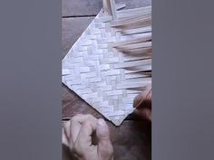 someone is working on a woven piece of material with wood shading in the background