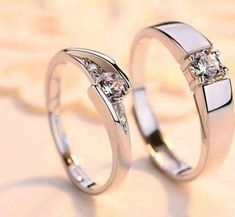 two white gold wedding rings with diamonds on each one, set against a beige background