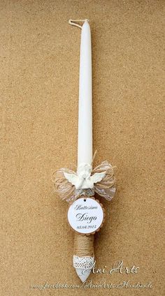 a white candle with a tag on it sitting next to a cork holder and ribbon