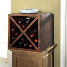 a wooden wine rack with several bottles in it and a bowl on top of it