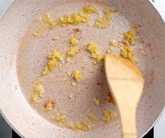 a wooden spoon stirring eggs in a pan