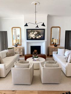 a living room filled with white couches and chairs next to a fire place in front of a fireplace