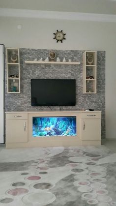 a living room with a large television on the wall and an aquarium in the center