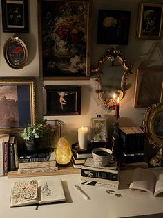 a desk with books, candles and pictures on the wall next to eachother