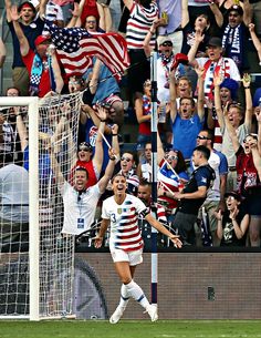 a group of people watching a soccer game with fans in the stands and one person holding an american flag