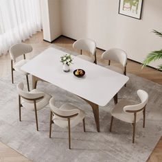 a dining room table with white chairs and a bowl of fruit on the center piece