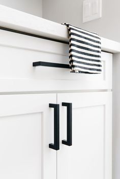 a black and white striped towel hanging on the side of a kitchen cabinet with handles