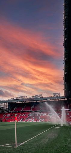 a fire hydrant spewing out water onto a soccer field at sunset or dawn