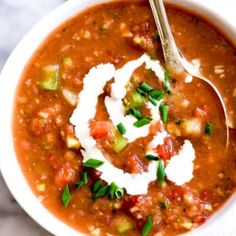 a close up of a bowl of chili soup with sour cream and chopped green onions