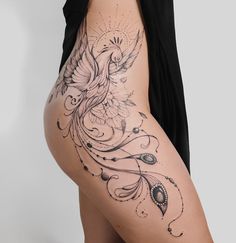 a woman's thigh with a bird tattoo on the side and an intricate design