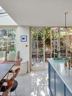 a kitchen with blue cabinets and counter tops next to a dining room table in front of an open glass door