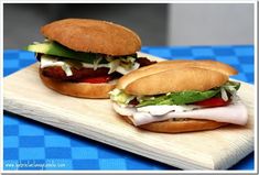 two sandwiches sitting on top of a wooden cutting board