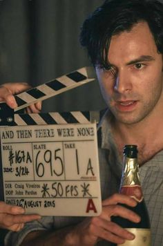 a man holding a bottle and a movie clapper